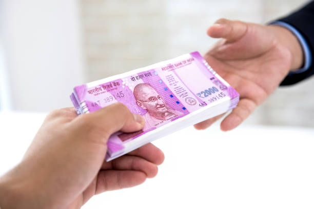 Businessman handing over Indian rupee banknote money Businessman handing over wad of crisp new Indian rupee banknote money to his partner against white blur background corruption photos stock pictures, royalty-free photos & images