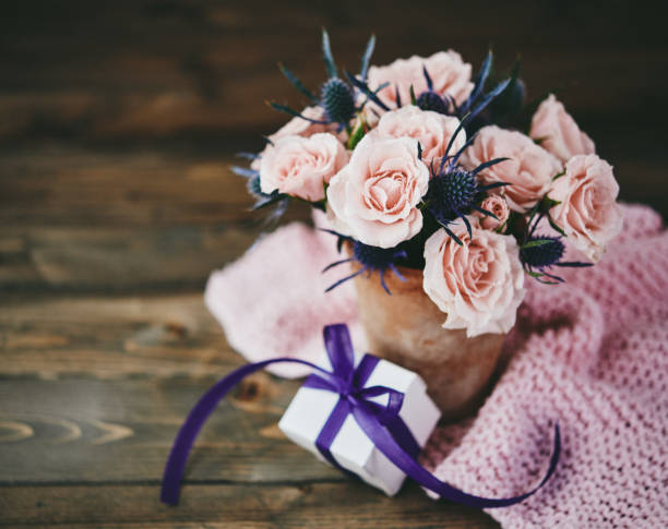 istock Handmade Mother's Day bouquet with pink roses and gift in rustic setting 946722950