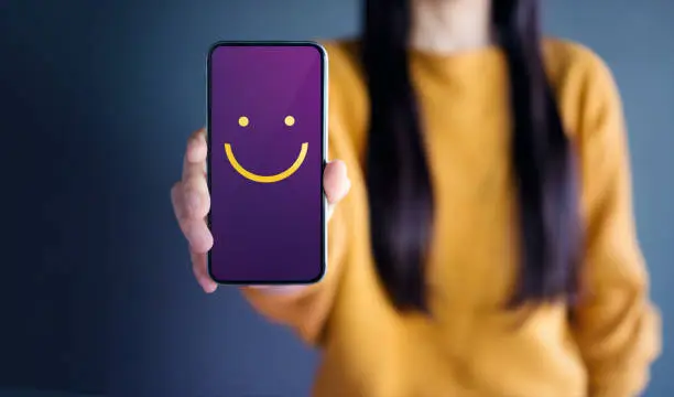 Photo of Customer Experience Concept, Happy Woman Show Smiley Face for her Satisfaction on Smart Phone