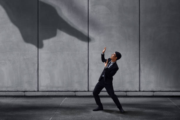 istock Stressed Businessman in Under Pressured Concept, Small Worker Scared a Shadow of Huge Pointing Hand. Terrible Boss or Customer 946745156