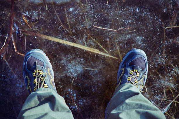 istock Man in hiking boots is standing on a frozen lake 946776686