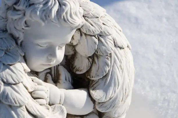 Sleeping angel statue.Angel guardian sleeping in white snow background