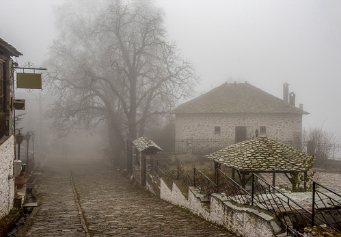 Fog and traditional stone houses in Vizitsa village on mountain Pelion. Greece.