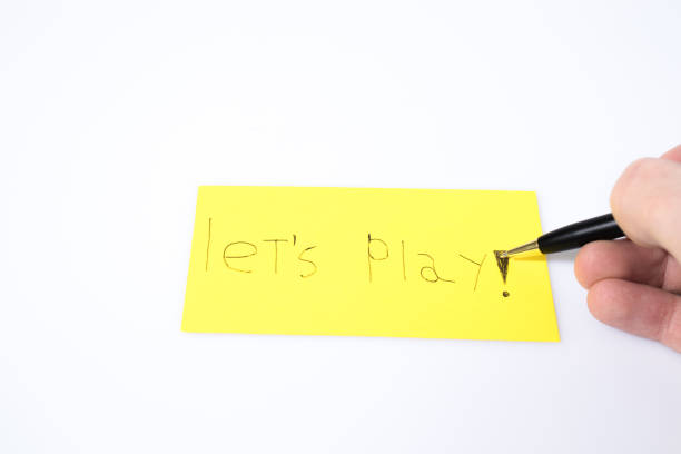 istock Let's play handwrite with a pen and a hand on a yellow paper composition 946802642