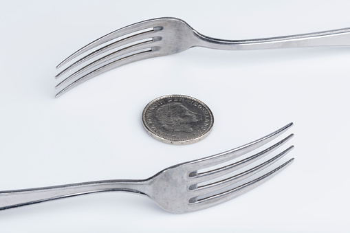 Conceptual representation of financial greed by two forks and coins