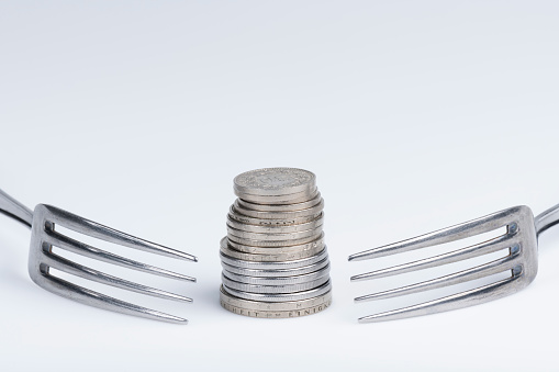 Conceptual representation of financial greed by two forks and coins