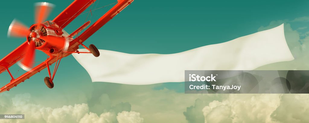 Airplane flying in the sky with a  banner Vintage red airplane flying in the sky with a white blank banner Airplane Stock Photo