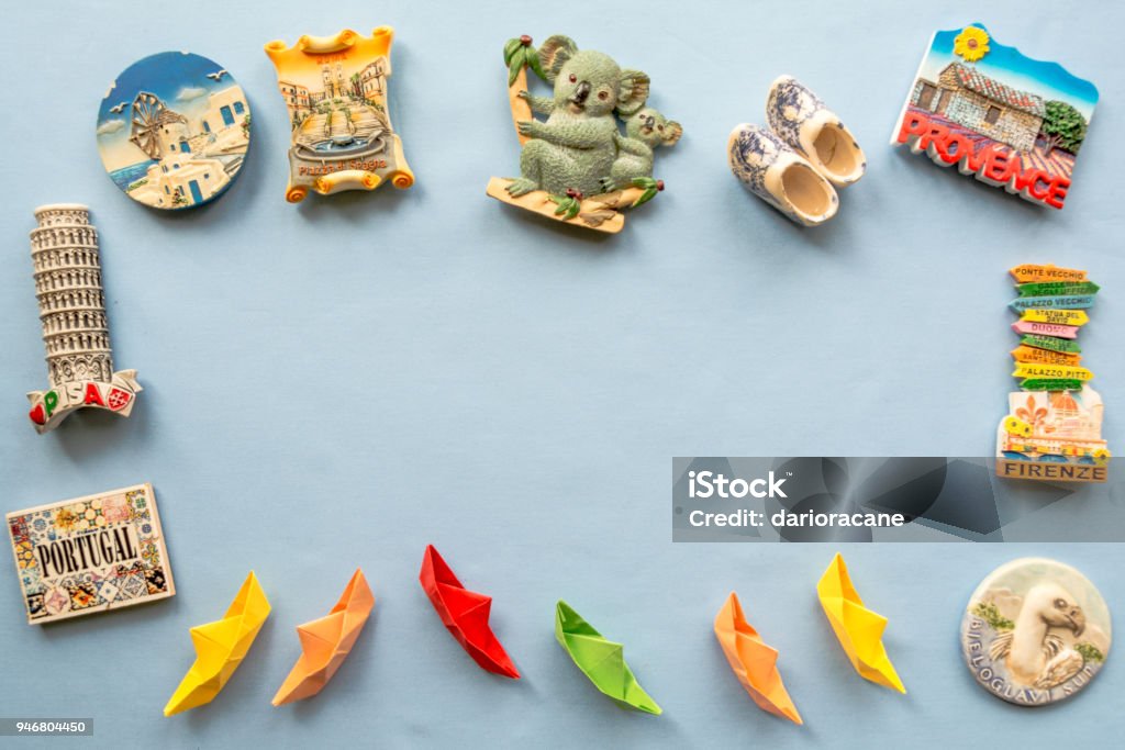 vários ímãs de lembrança e navios de papel, dispostos sobre o fundo azul - Foto de stock de Geladeira royalty-free
