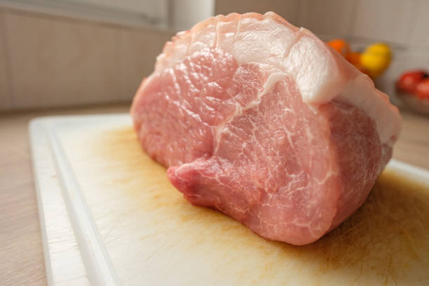 Raw roasting pork from the shoulder with rind on a cutting board
