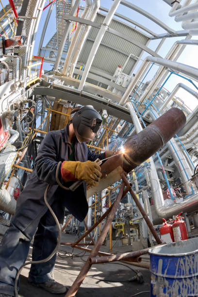 Welding works at installation of the new pipeline on oil refining installation with use of manual arc welding. Fisheye view