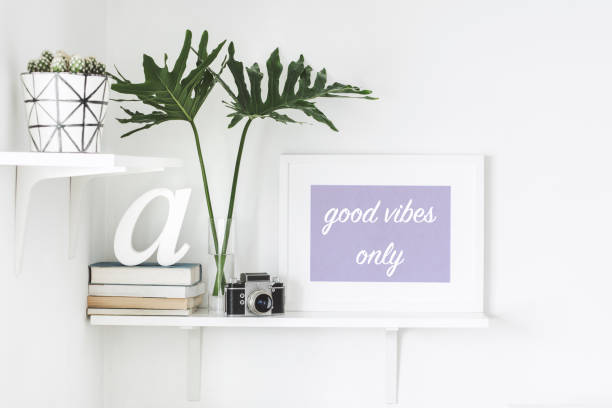 istock Stylish scandi interior with white shelf , mock up frame, books, camera and leafs . 946819934