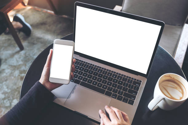 istock mockup image of hands holding blank mobile phone while using laptop with blank white desktop screen 946823162