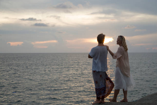 istock Couple look out to sea at sunset 946824254