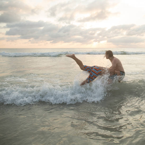 istock Men tackle each other into sea 946824588