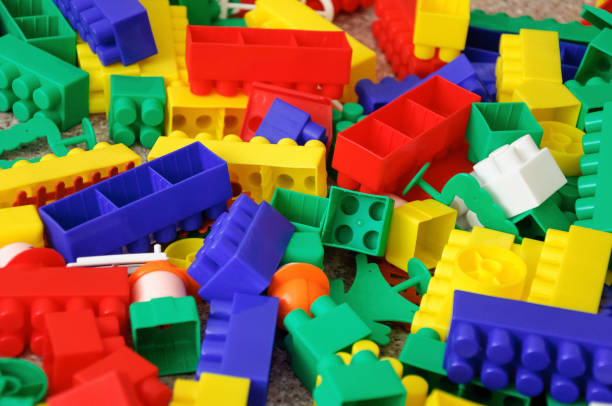 istock Children toys. Multi colored plastic constructor with blocks for building houses and cars, plain, bus with figures of people 946825514