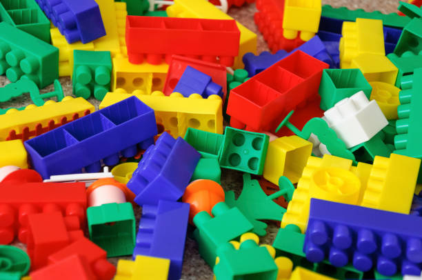 istock Children toys. Multi colored plastic constructor with blocks for building houses and cars, plain, bus with figures of people 946825562
