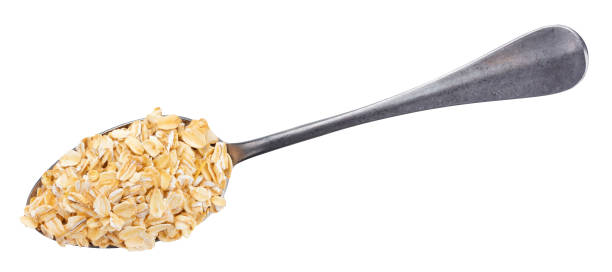 istock Oat flakes in spoon isolated on white background. Top view 946834470