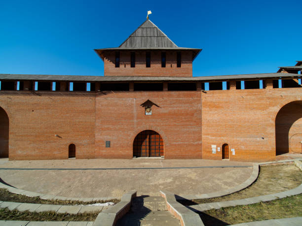 Long brick corridor in Nizhny Novgorod kremlin captured at angle, showcasing intricate brickwork. Natural light filters through windows, creating rhythmic shadows and highlighting warm colors