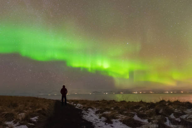 fenômeno da aurora boreal (luzes do norte) no inverno. fotógrafo de pé sob tempestade solar aurora polaris acima de sua cabeça à noite na islândia - aurora borealis iceland astronomy tranquil scene - fotografias e filmes do acervo