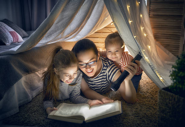 istock Mom and children reading book 946853616