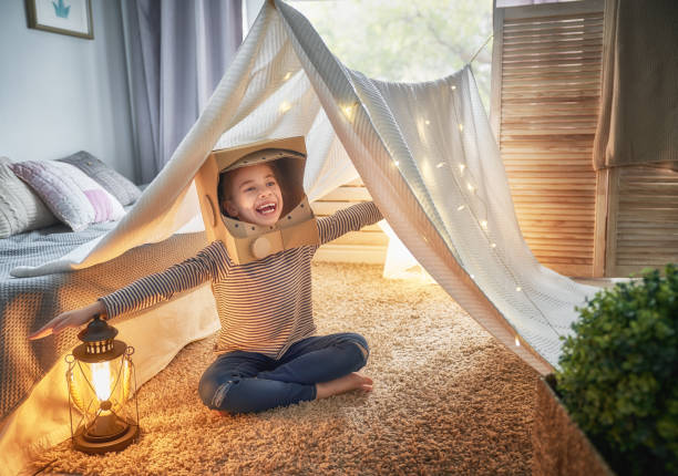 kid playing in tent Child in an astronaut costume dreaming of becoming a spacemen. Happy kid playing in tent. Funny lovely girl having fun in children room. cardboard house stock pictures, royalty-free photos & images