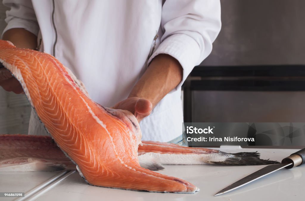 La mano dello chef che tiene un pezzo fresco di salmone - Foto stock royalty-free di Pesce