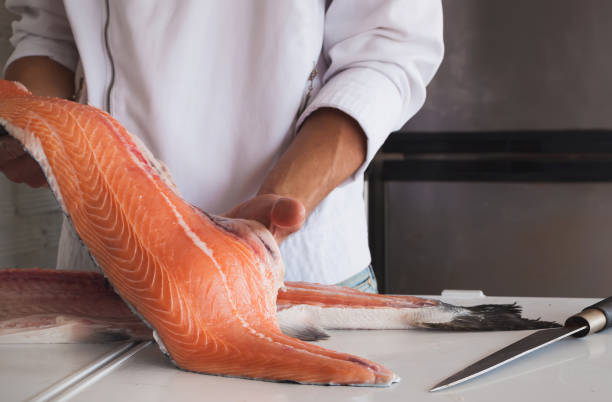 la mano dello chef che tiene un pezzo fresco di salmone - salmone frutto di mare foto e immagini stock