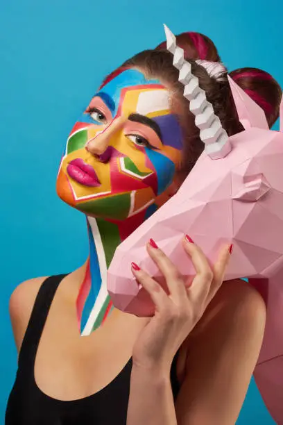 Photo of Pop art portrait of model wearing colorful figures on her face.