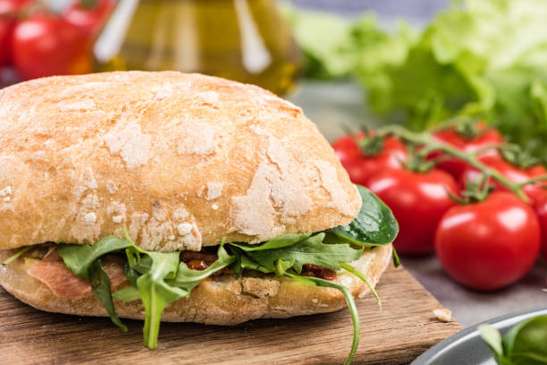 istock Fresh bun with rocket salad on wooden board 946865366