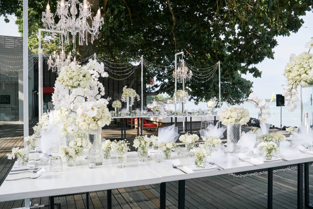istock Wedding reception dinner table setting with a lot of white roses, flower, floral decoration 946872638