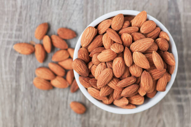 istock Pile of almonds nut in a while bowl against wooden background select focus shallow depth of field 946872890
