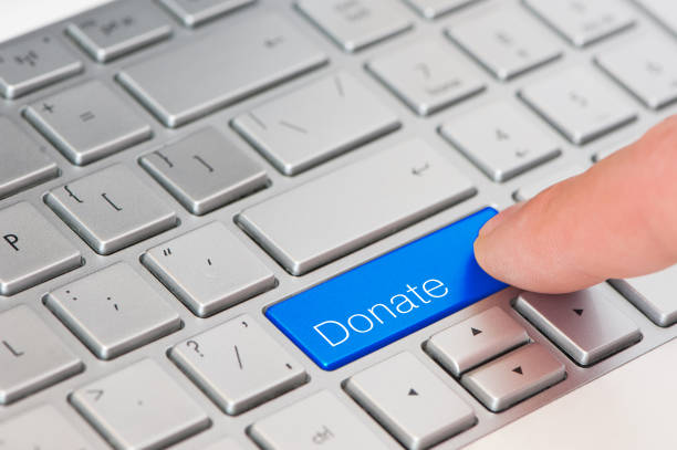 A finger press blue Donate button on laptop keyboard stock photo