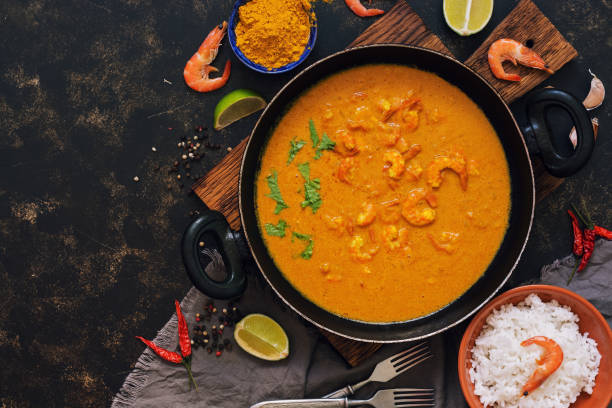 istock Shrimp in curry sauce with rice on a dark background. Thai Indian dish. Top view, copy space. Asian food. 946874134