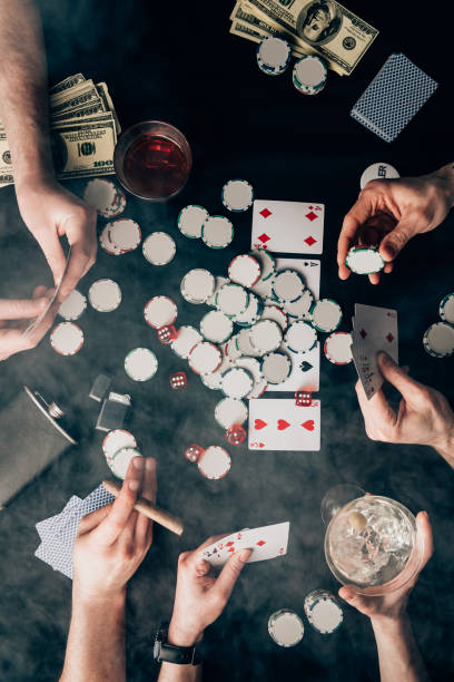 istock Smoke over people playing poker by casino table with cards and chips 946887572