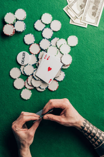 istock Man holding poker cards by casino table with chips 946887916