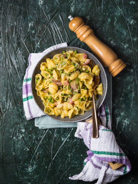 orecchiette nudeln mit erbsen und speck - orecchiette stock-fotos und bilder