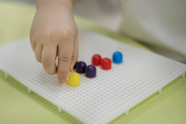 centered child plays in the sorter at the table actividades para niños. actividad motora fina simple de la habilidades para los niños. excelente manera de enseñar a un niño o un niño en edad preescolar para sostener el lápiz correctamente para la escritura. preparar a un niño las actividades de l