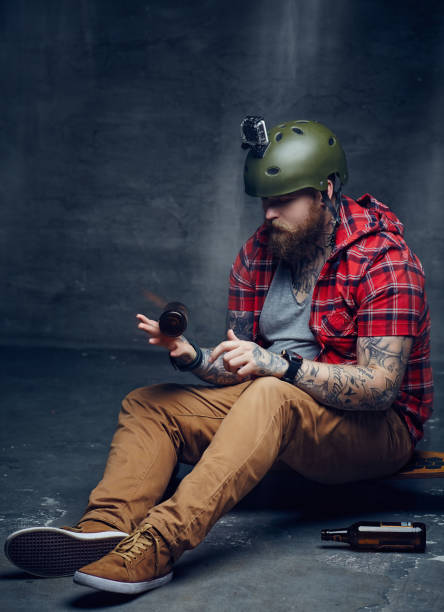 istock Bearded man in red shirt sitting on long board. 946897872