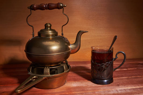 istock Still life with a brass teapot, which is located on a stand for coal, glass cup with tea, a teaspoon and a  cup metal holder 946905766