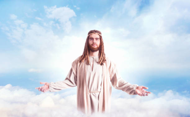 istock Jesus Christ with open arms against cloudy sky 946908466