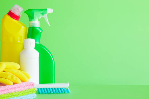 istock Colorful cleaning set for different surfaces in kitchen, bathroom and other rooms. Empty place for text or logo on green background. Cleaning service concept. Spring regular clean up. Front view. 946909682