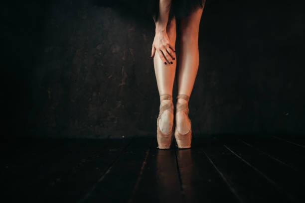 istock Ballet dancer legs in pointes, black wooden floor 946912544
