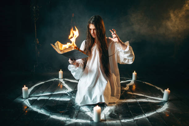 istock Woman sitting in burning pentagram circle, magic 946913666
