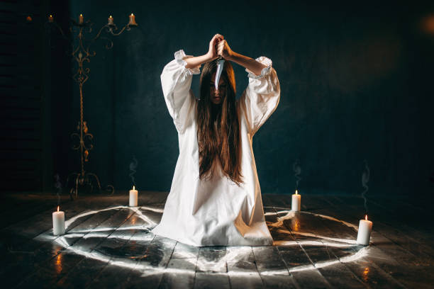 istock Woman with knife sitting in pentagram circle 946913770