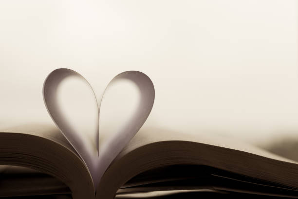 Heart-shaped paper inside a book. The shape of the heart is known worldwide as a symbol of love and unity. book heart shape valentines day copy space stock pictures, royalty-free photos & images