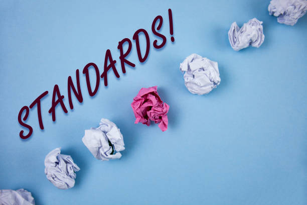 istock Handwriting text writing Standards Motivational Call. Concept meaning Quality Controls Regulations Guidelines written on Plain Blue background Crumpled Paper Balls next to it. 946934768