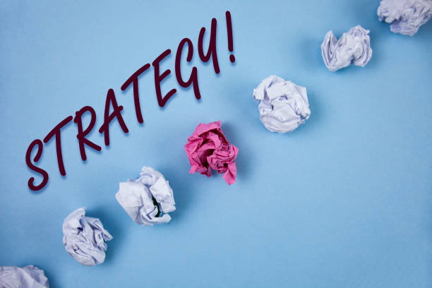 istock Handwriting text writing Strategy Motivational Call. Concept meaning Group of ideas planned to achieve success written on Plain Blue background Crumpled Paper Balls next to it. 946934936