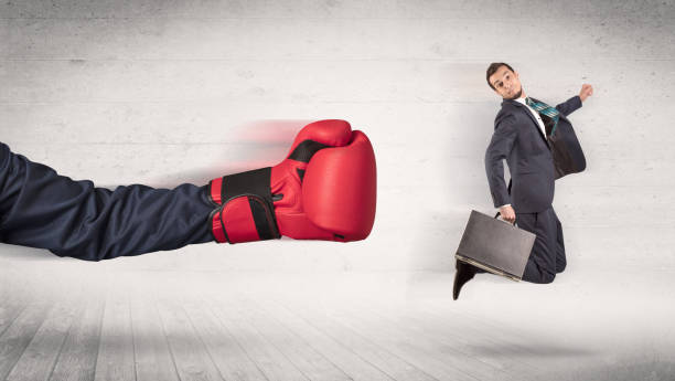 istock Arm with boxing gloves hits office worker concept 946936040