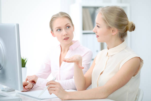 istock Two business ladies or colleagues discussing something in office background 946941390