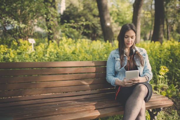 istock Smiling woman in park using digital tablet 946945722